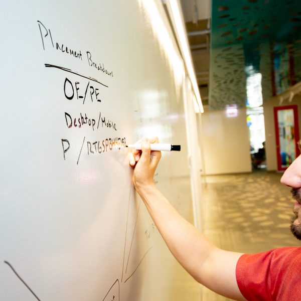 Image of a man writing on a whiteboard with a marker.