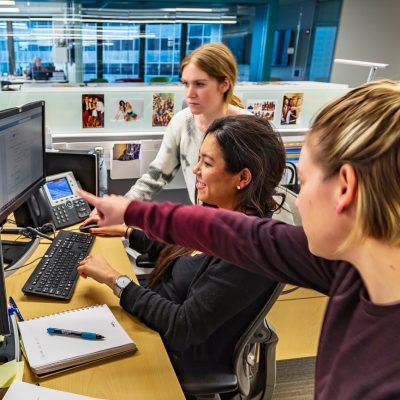 Three KSM employees sitting around a computer discussing work.