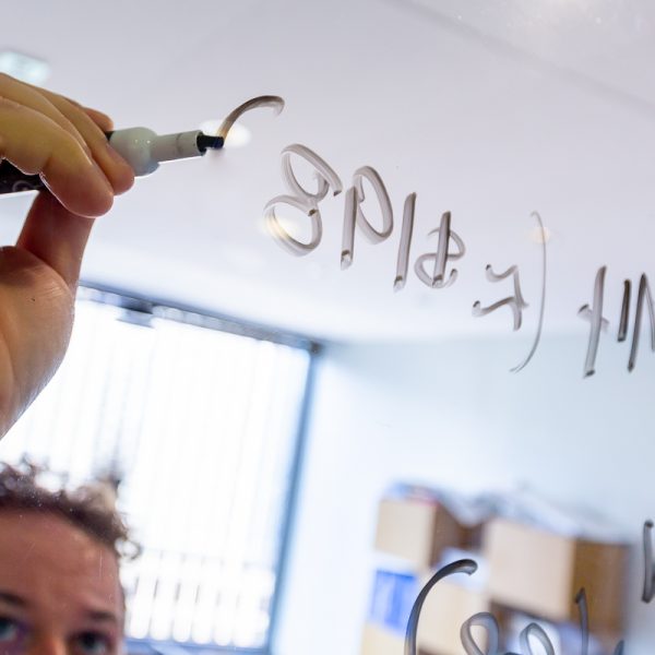 person writing on glass with dry erase marker