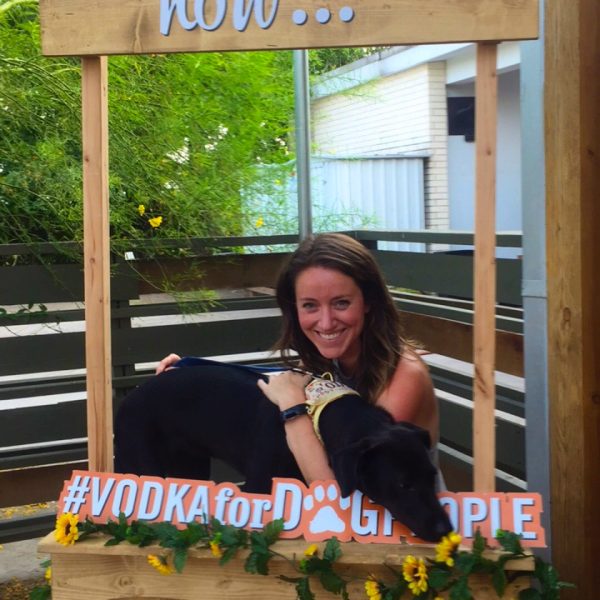 Image of a woman holding a black lab dog at a kissing booth.